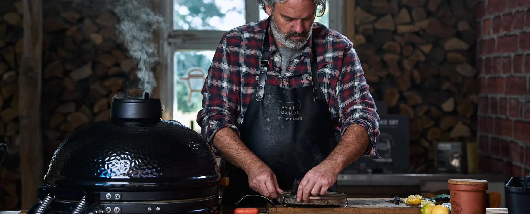 Stephan Stohl bereitet am geschlossenen MONOLITH Kamado Fisch vor, aus dem Deckel steigt Rauch